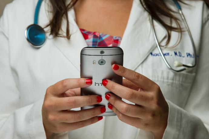 Una doctora revisando su celular para ver los resultados de las pruebas ADN para diagnóstico de enfermedades